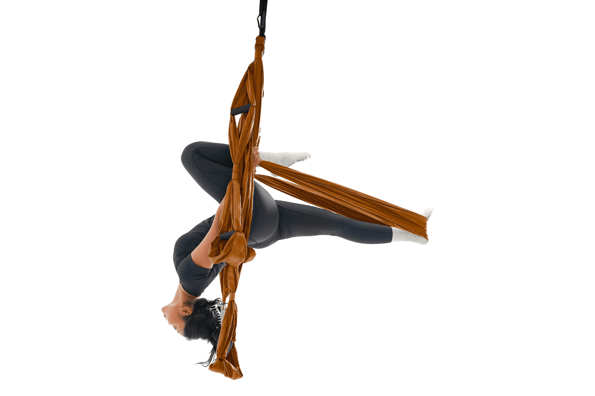 Woman hanging upside down in a Terracotta Orange Yoga Hammock, holding the handles with her legs extended